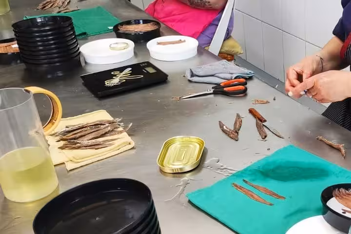 Workers hand-process anchovies at a factory in Santoña, showcasing traditional methods of anchovy preservation.
