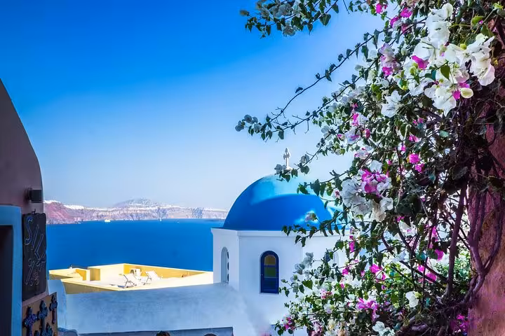 Santorini blue-domed church and bougainvillea overlooking the caldera on a 5-day private tour from Athens