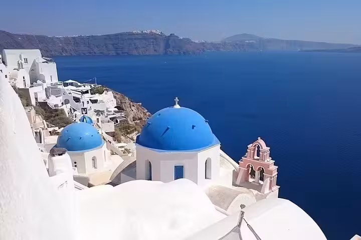 Blue-domed church rooftops overlooking the Santorini caldera in Oia on a private half-day sightseeing tour