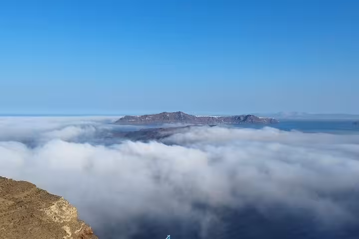 Santorini caldera rising above a sea of clouds, panoramic viewpoint on a one-day Santorini escape tour