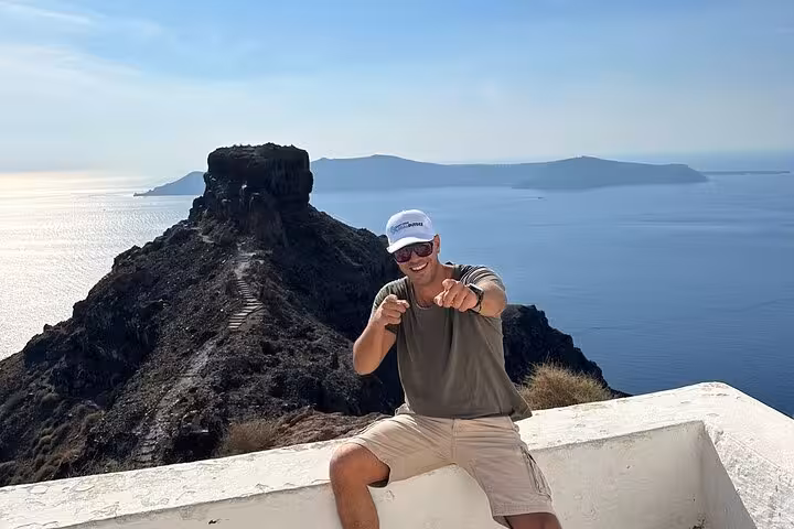 Tour guest at Santorini caldera viewpoint near Skaros Rock, scenic photo stop on cruise shore excursion