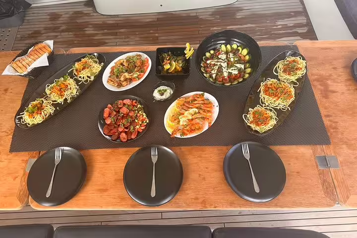 Gourmet meal spread on a catamaran featuring fresh seafood and Mediterranean dishes during Santorini cruise.