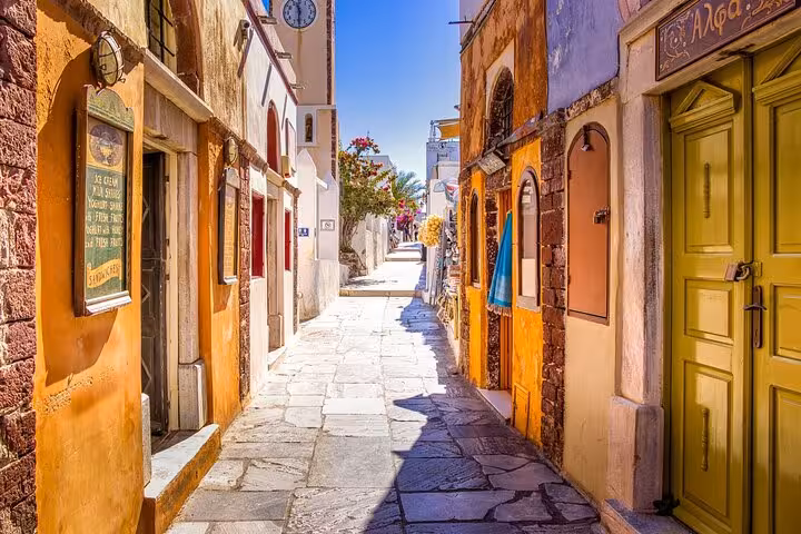 Charming Santorini alley with colorful doors and stone path, walking tour highlight on 2-day trip from Athens