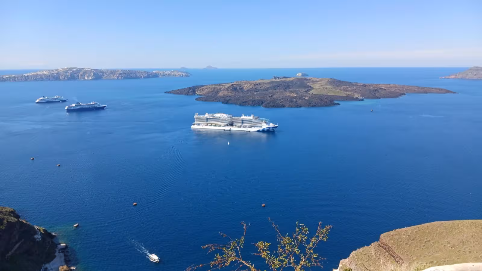 Cruise ships anchored in Santorini caldera with volcanic islets, a highlight on the 5-hour Shore to Oia tour