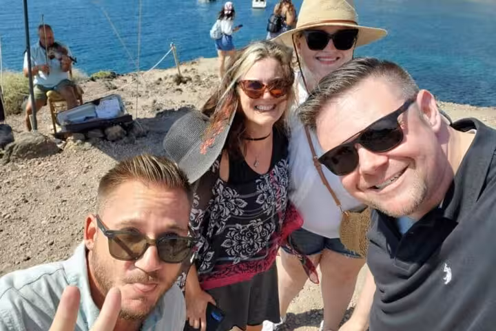 Happy travelers on Santorini cliffside by the sea during private day trip from Crete with transfers