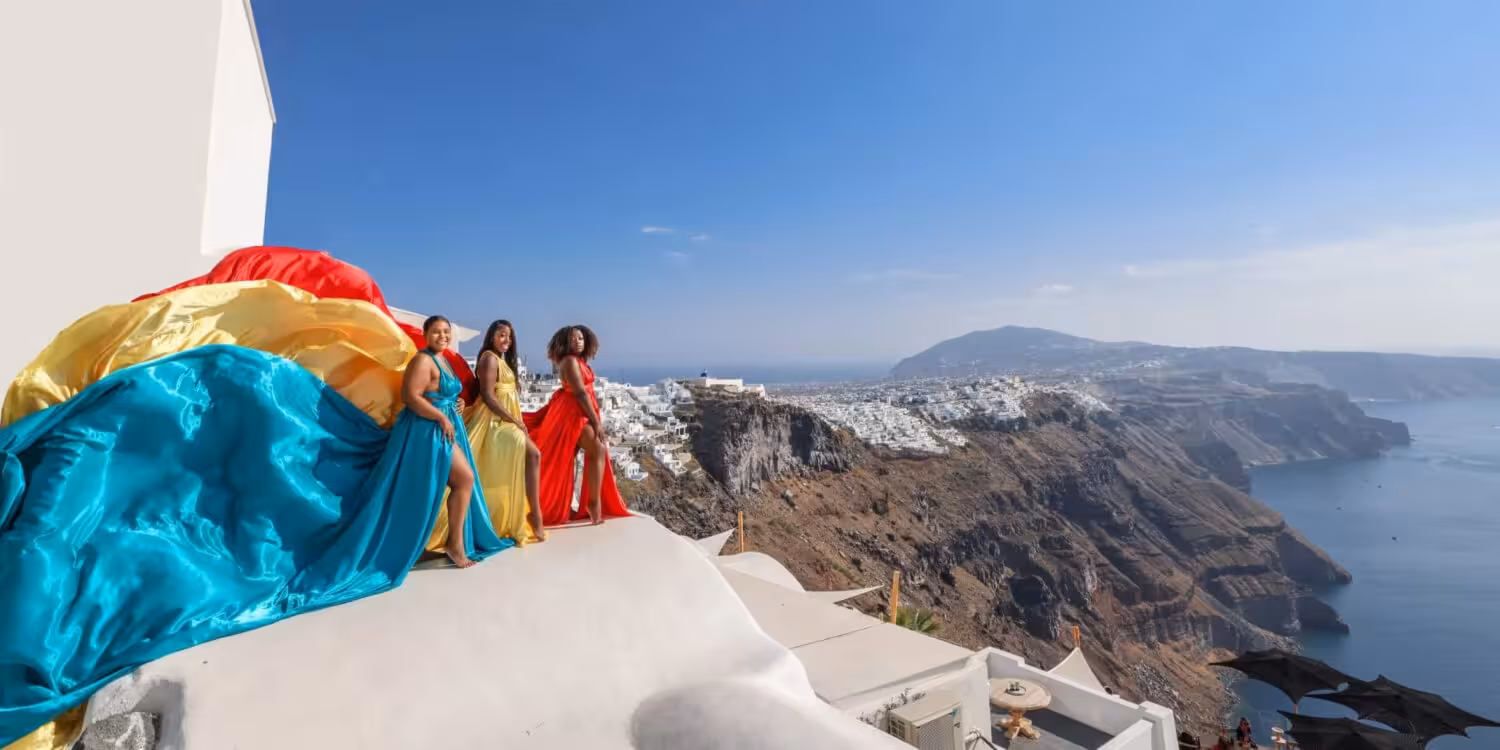Flying dress photoshoot in Santorini with colorful gowns on a rooftop, caldera cliffs and Aegean sea panorama