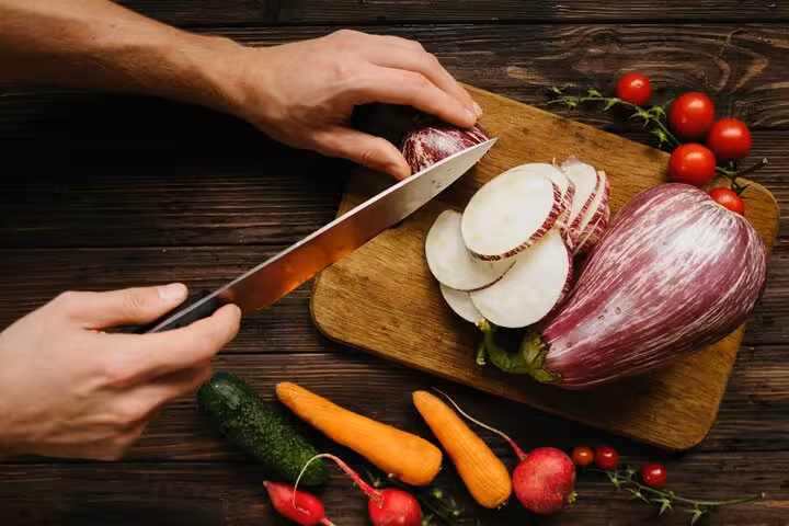 Hands slicing eggplant with fresh tomatoes and vegetables, Greek cooking class prep with caldera view vibes