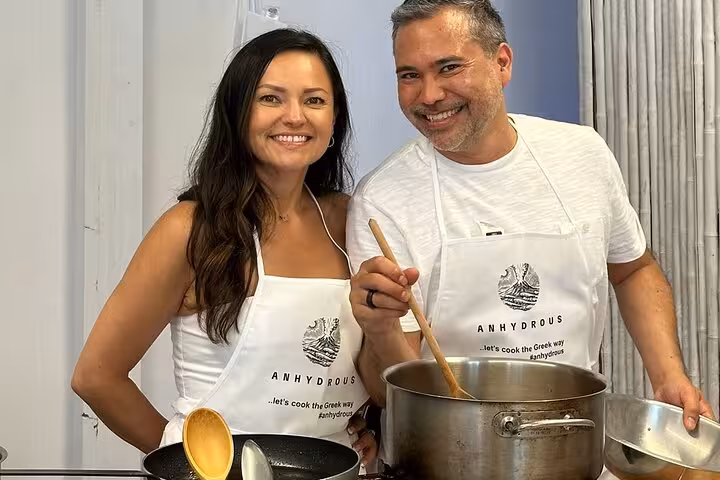 Honeymoon couple cooking Greek food in Santorini class, stirring pot before visiting two local wineries