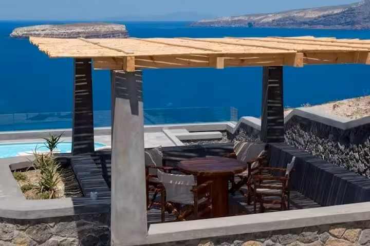 Luxury Santorini villa terrace with pergola dining and caldera sea views, ideal for day getaway with transport
