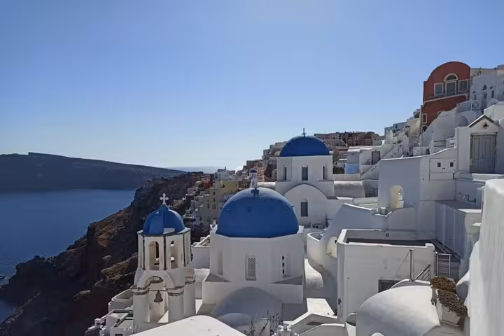 Oia cliffside with blue-domed churches overlooking the caldera, Santorini private 3-day tour transfer