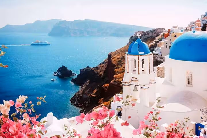 Oia blue-domed church and caldera cliffs with cruise ship, iconic Santorini villages and wine tour scenery