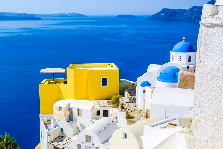 Santorini Oia whitewashed houses and blue domes above the caldera, 2-day tour from Athens to Mykonos