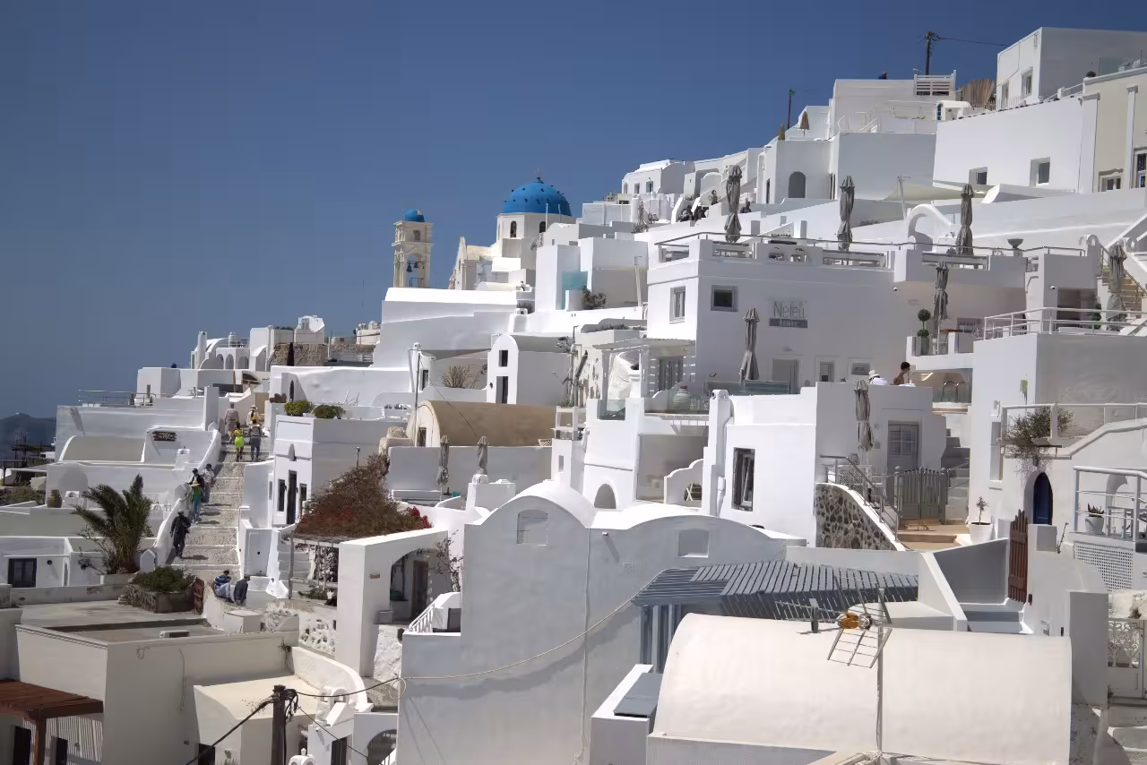 Whitewashed Santorini village with blue dome church, scenic stop on shore excursion from cruise port to Oia
