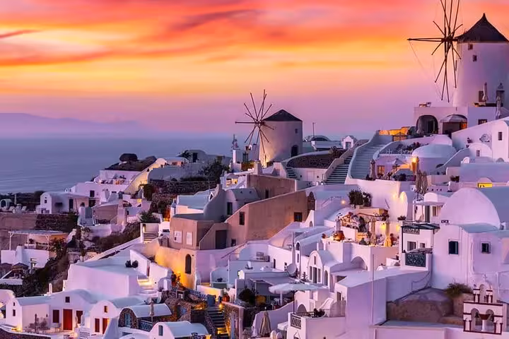 Santorini Oia windmills and whitewashed cliffside at sunset on 7-day Athens Mykonos Santorini Greece tour