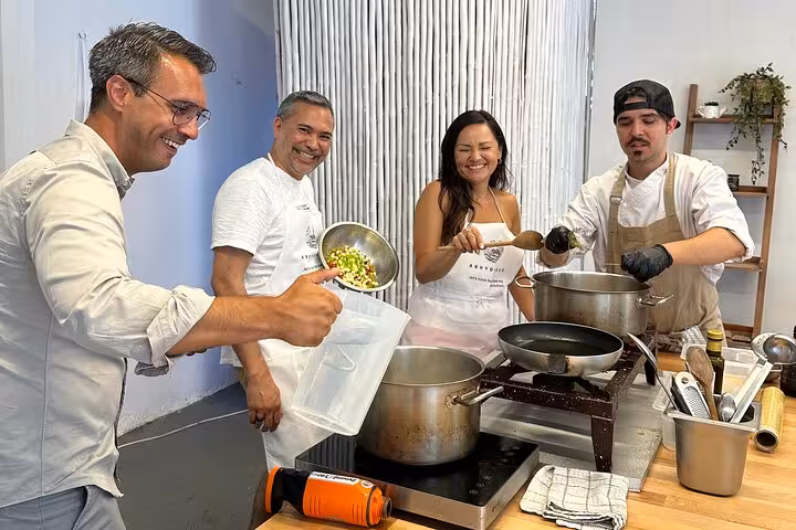 Guests cook Greek recipes in a Santorini private cooking class, stirring pots and prepping ingredients indoors