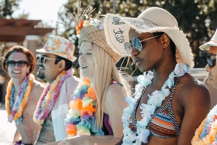 Friends in leis and sun hats relaxing by a private pool, Santorini caldera and sunset view day tour