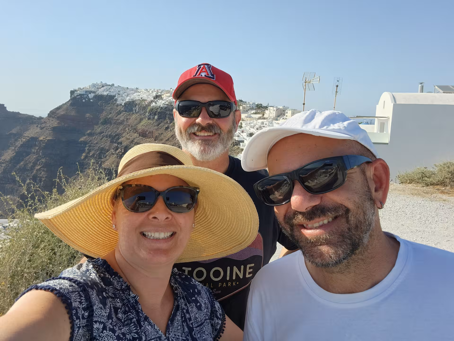 Group selfie at Santorini caldera cliffs on private tour, whitewashed villages and sea views in the background