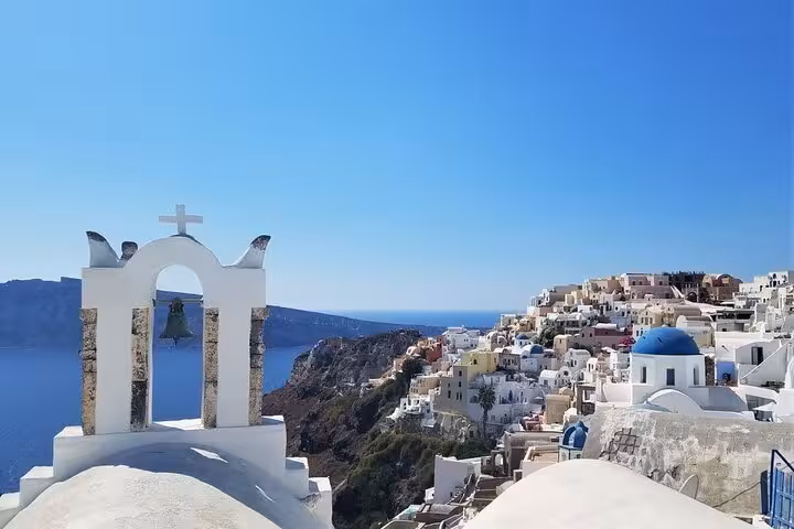 Santorini private tour view of Oia whitewashed cliffs, blue-domed church and caldera sea under clear sky
