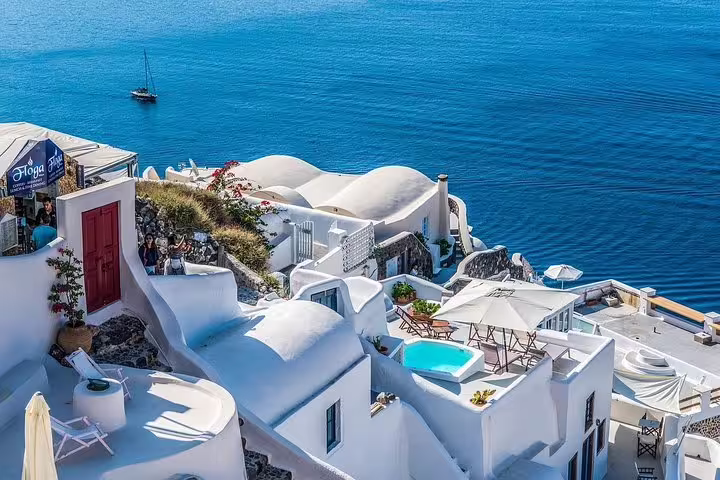 Whitewashed buildings with blue domes overlook the Aegean Sea in Santorini, Greece, perfect for a private full-day tour.
