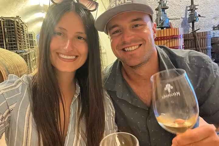 Couple enjoying Santorini winery cellar tasting on a private wine tour, sampling local Assyrtiko wines