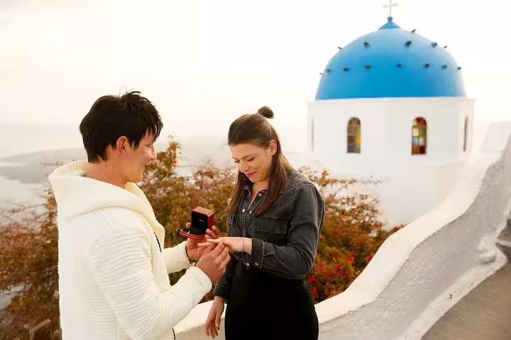 Romantic Santorini proposal by blue-domed church in Oia, personal photographer capturing ring moment at sunset