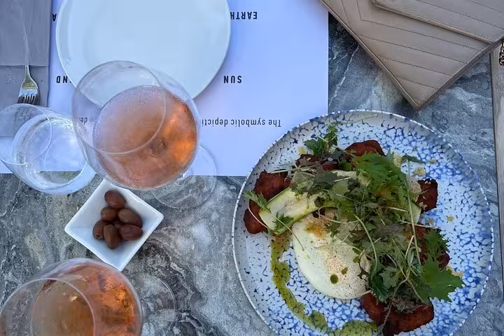 Rosé wine and Greek lunch plate on marble table during Santorini private wine tasting tour with food pairing
