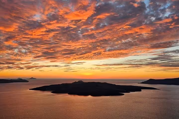Santorini caldera sunset panorama on a private romantic wine tour, dramatic orange clouds over the Aegean Sea