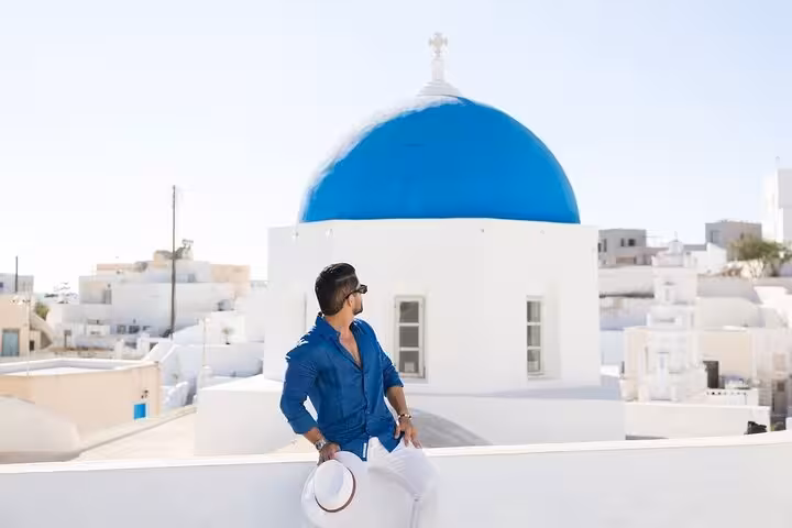Traveler by blue-domed church in Santorini, a highlight of Thera one-day island tour with lunch and wine tasting