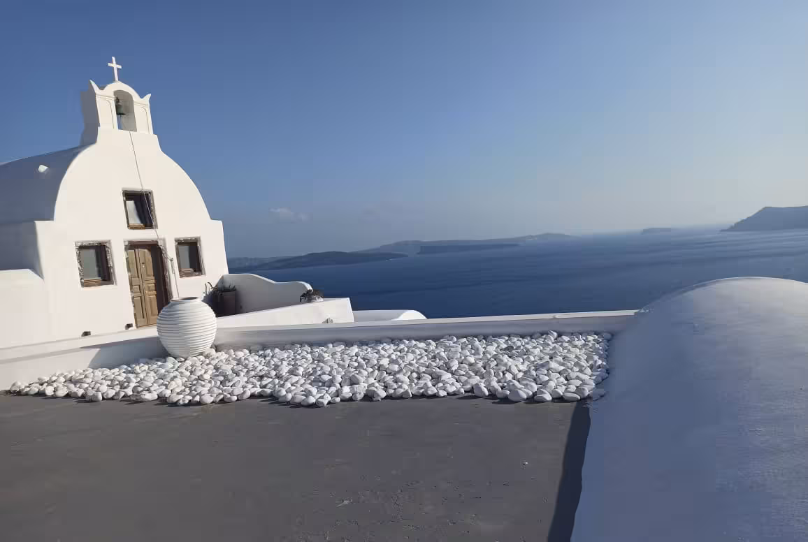 White chapel rooftop terrace overlooking Santorini caldera, scenic photo stop on Shore to Oia cruise excursion