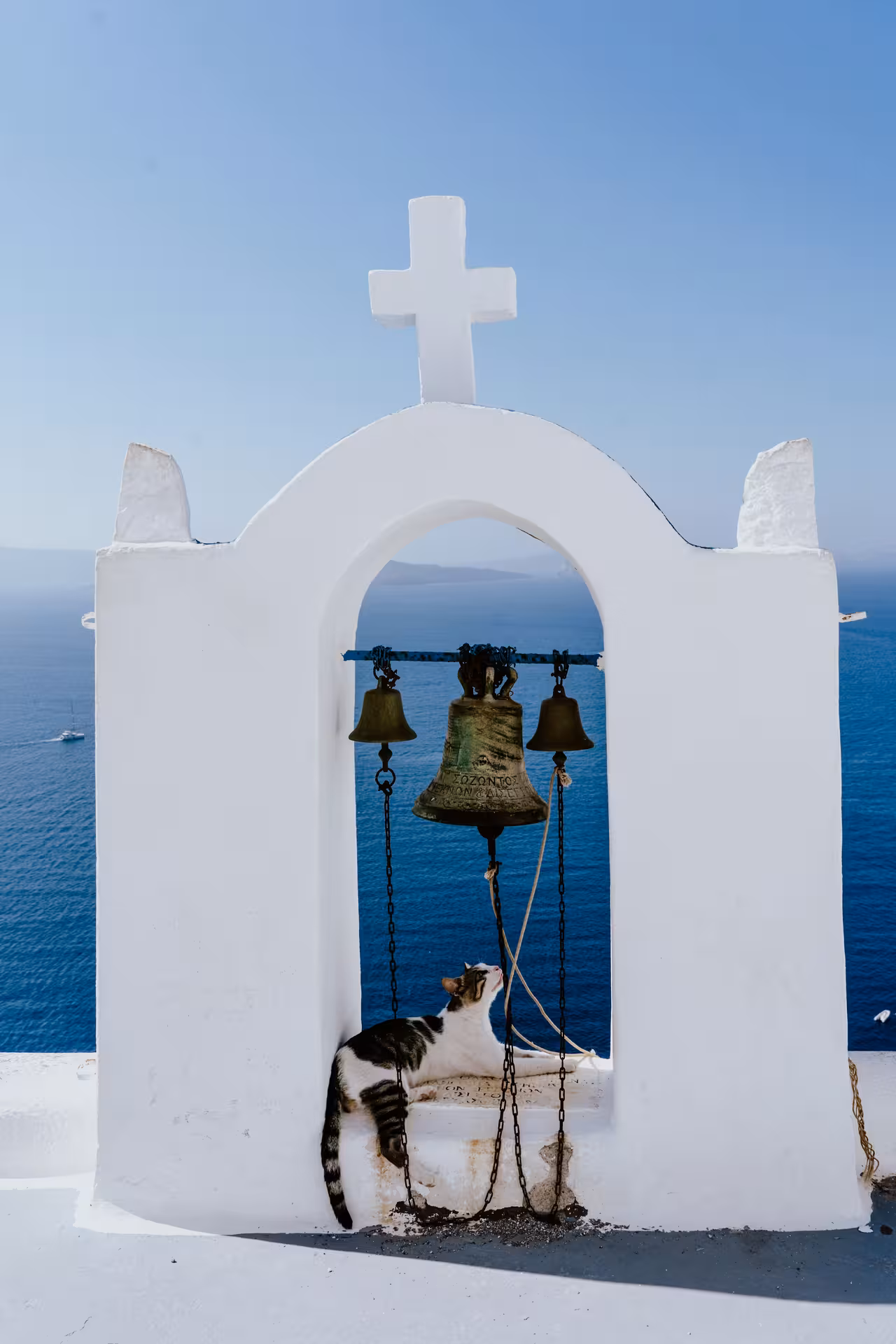 White Santorini church bell tower with cross and sea view, classic stop on Santorini iconic highlight tour