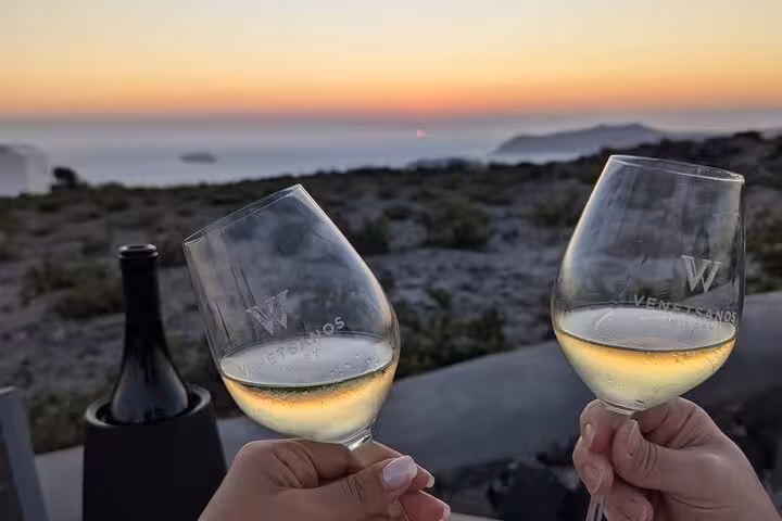 Close-up of wine glasses at Santorini sunset, romantic private honeymoon wine tasting with caldera sea views
