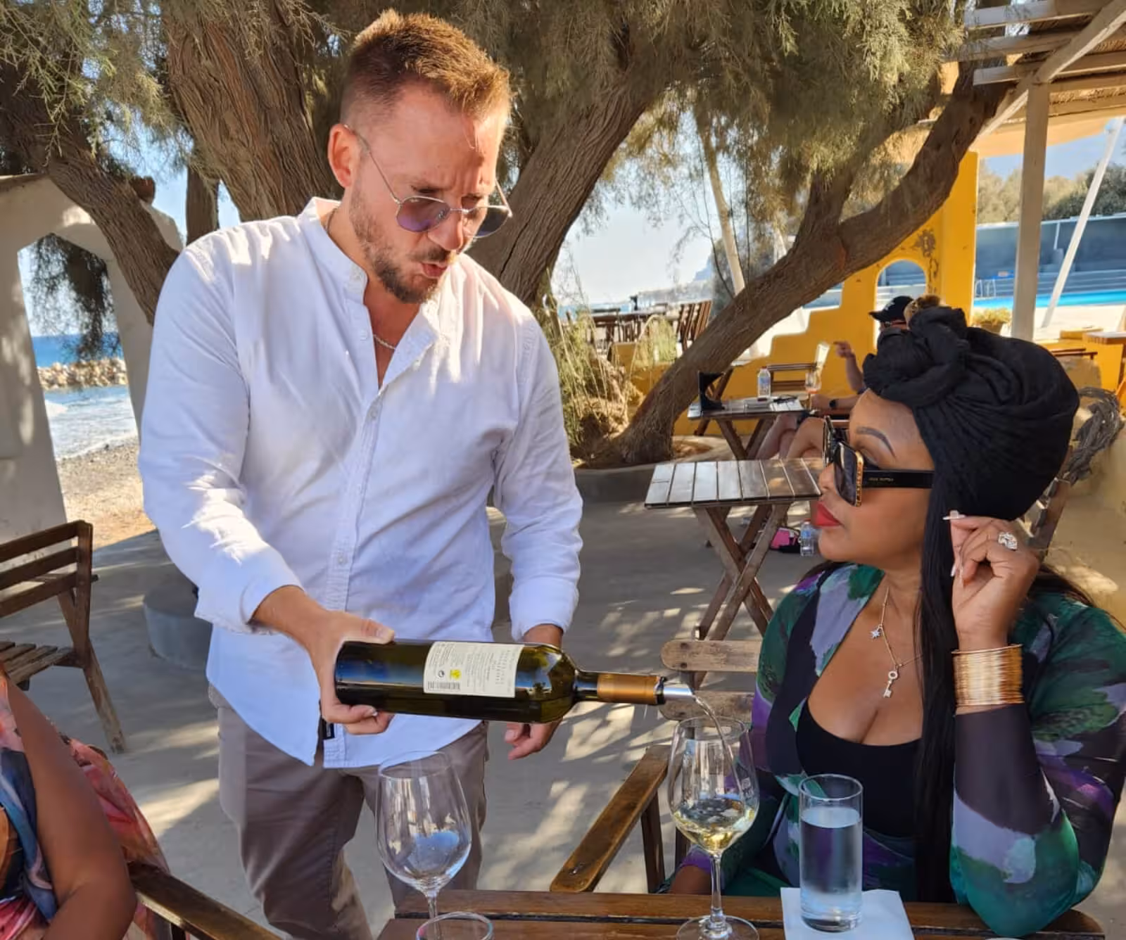 Wine tasting stop on Santorini private tour, sommelier pouring local white wine at seaside taverna