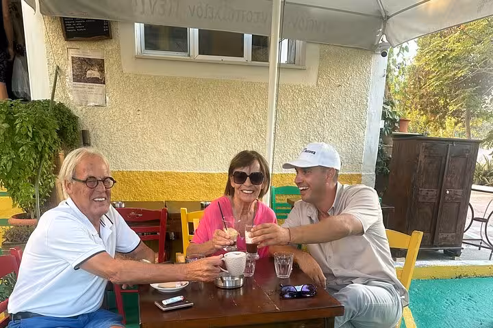 Guests toasting local wine at a Santorini taverna during Island of Thera 8-hour tour with lunch and winery tasting