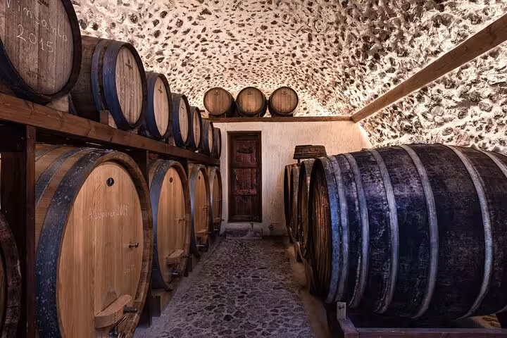 Wine cellar with oak barrels at Santorini winery, highlight of Santorini private tour from Athens wine tasting
