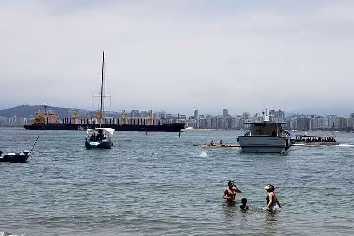 Scenic view of Santos beach with boats and city skyline, ideal for a private boat tour with barbecue and drinks included.