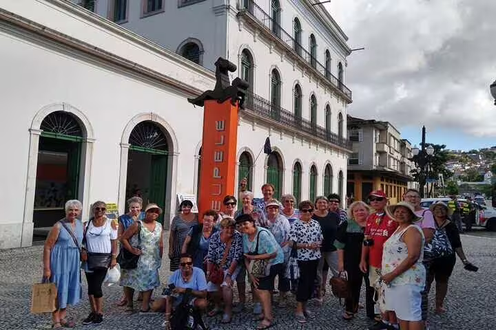 Visitors pose by the historic coffee museum in Santos during an engaging full-day tour with lunch included.