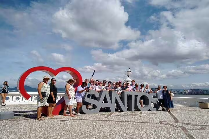 Tour group enjoying the Santos sign on a scenic 10-hour beach tour with clear skies and ocean views.