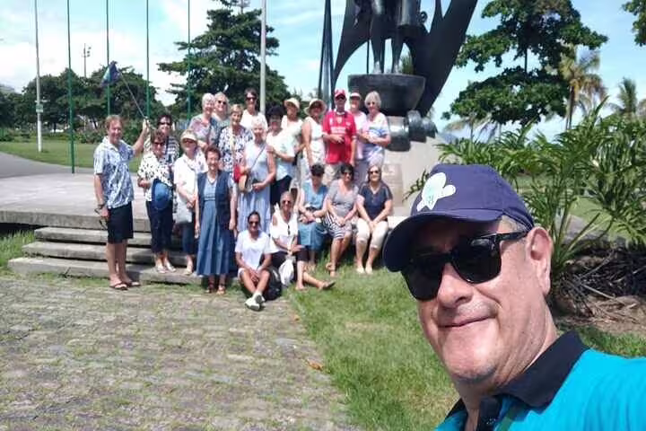Group of tourists posing by a monument in a park during the shared full-day Santos beach tour.