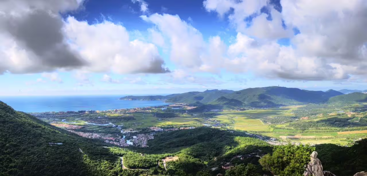Panoramic view of Sanya's vibrant coastline and rolling hills, perfect for a cultural experience city break.