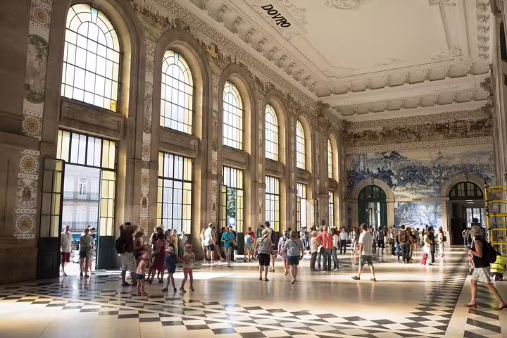 Visitors admire the grand blue-tiled walls of São Bento Station, a highlight of the Essential Porto Walking Tour.
