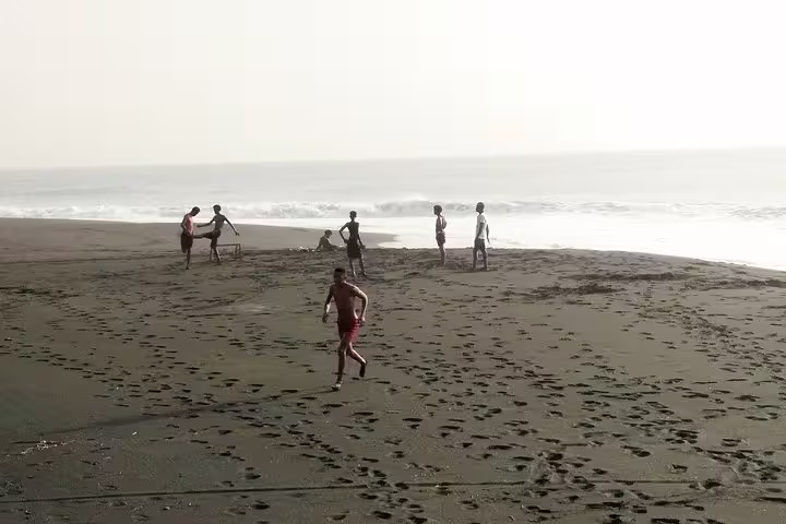 Visitors enjoy a leisurely game on São Filipe's black sand beach, perfect for relaxation after a Fogo volcano tour.