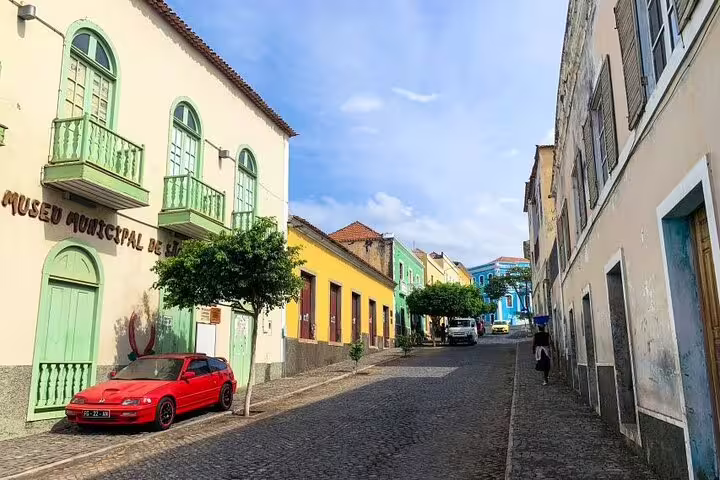 Colorful historic street view in São Filipe with vibrant buildings and a classic car, perfect for walking tours.