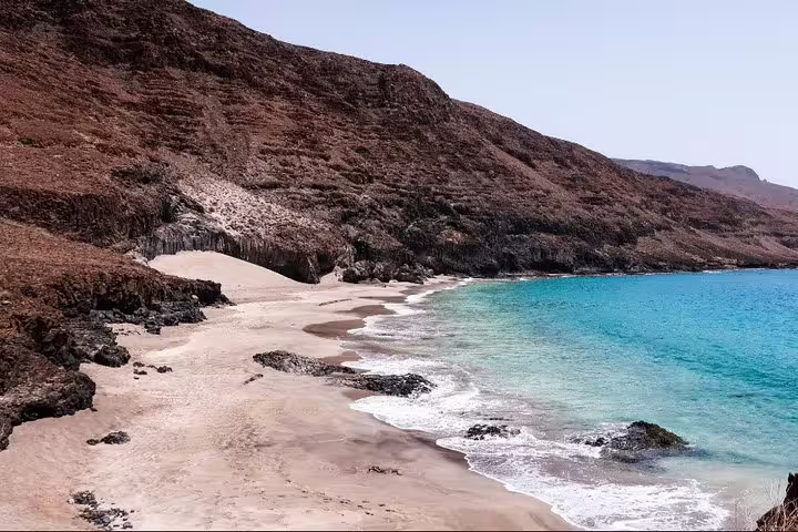 Pristine beach with turquoise waters and rugged cliffs, ideal for São Nicolau hiking tours to D’Boche de Rotcha.