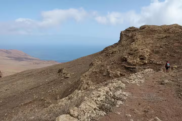 Hiker exploring rocky terrain with expansive ocean views on the Juncalinho Trail in São Nicolau, Cape Verde.