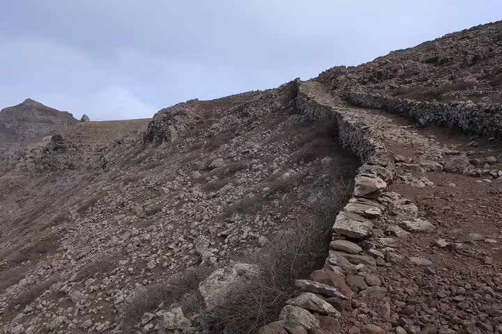 Steep, rocky path lined with stone walls on the Juncalinho Trail, offering rugged adventure in São Nicolau.