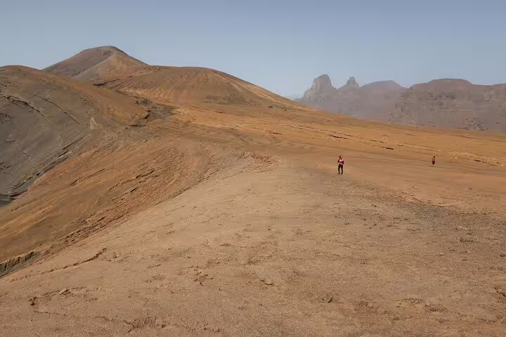 Expansive desert landscape of Praia Branca with hikers exploring the trails on São Nicolau island.