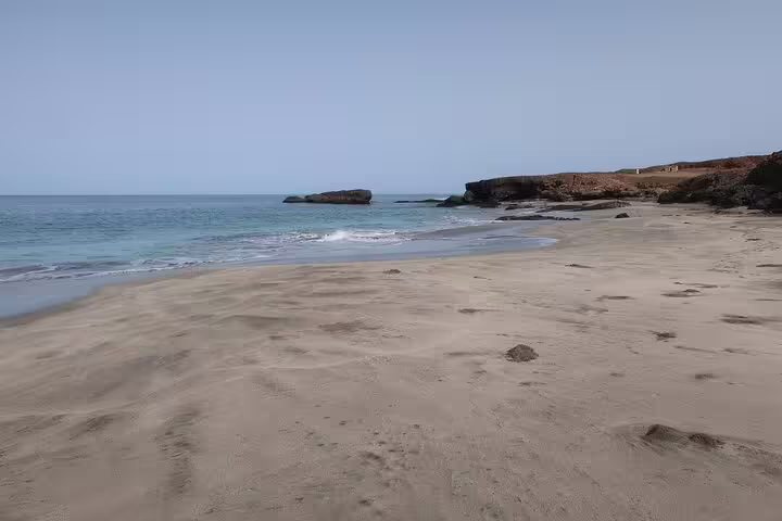 Serene sandy beach with gentle waves at D’Boche de Rotcha, perfect for hiking tours in São Nicolau.