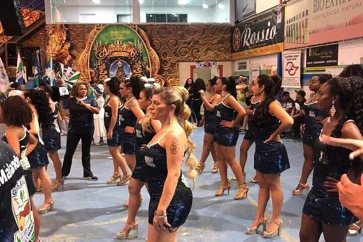 Group of women in sparkling blue dresses practicing samba dance moves at a São Paulo Carnaval rehearsal.