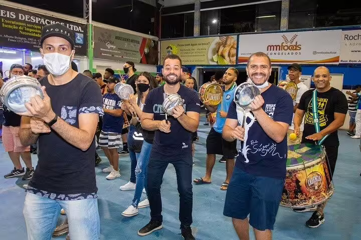 Musicians enthusiastically play traditional percussion instruments at a São Paulo Carnaval rehearsal, embodying vibrant cultural music.