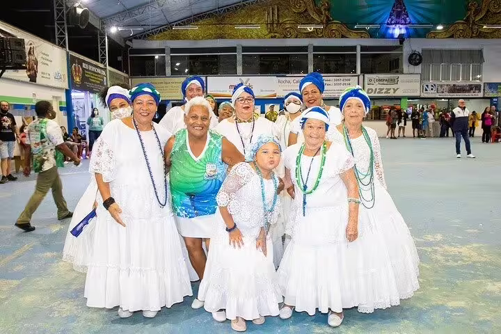 Group of women in traditional attire joyfully pose during a São Paulo Carnaval rehearsal, celebrating samba culture and unity.
